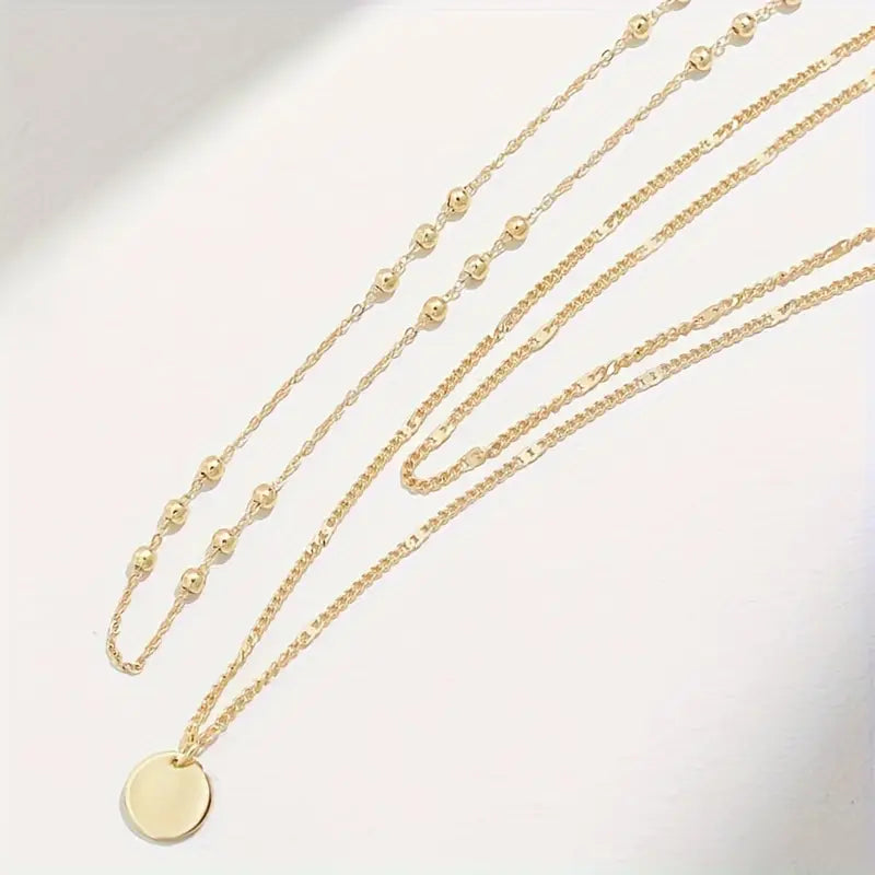 Erleben Sie schlichte Raffinesse mit unserem „Chic Tiers“-Anhänger-Set. Dieses dreilagige Kettenensemble aus hochwertigen, vergoldeten Eisenketten besticht durch seinen luxuriösen Glanz und seine dauerhafte Wasserfestigkeit – ideal für den täglichen Gebrauch und auf Reisen. Der mehrsträngige Scheibenanhänger setzt einen modernen, edlen Akzent, während das klare, elegante Design in strahlendem Gold eine zeitlose Ausstrahlung vermittelt. „Chic Tiers“ ist vielseitig kombinierbar.